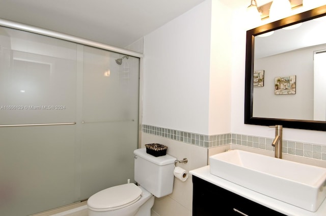 bathroom with tile walls, an enclosed shower, toilet, and vanity