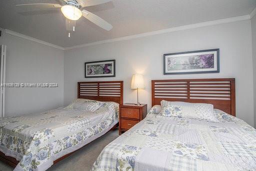 carpeted bedroom with ceiling fan and ornamental molding