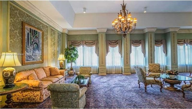 interior space featuring carpet floors, crown molding, ornate columns, a raised ceiling, and a chandelier