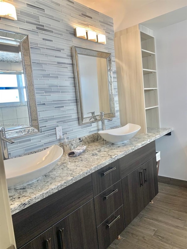 bathroom with dual bowl vanity, hardwood / wood-style flooring, and backsplash