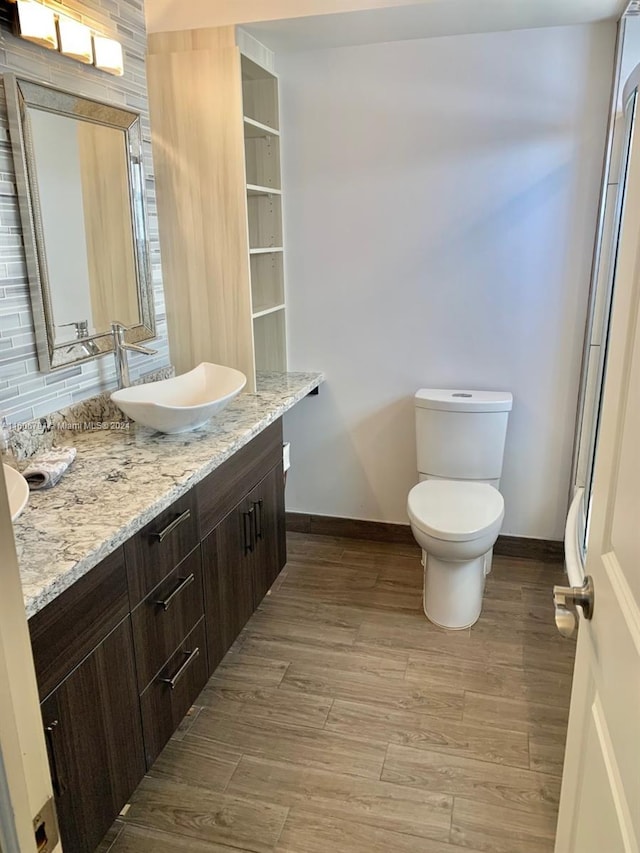 bathroom with hardwood / wood-style flooring, tasteful backsplash, toilet, and vanity