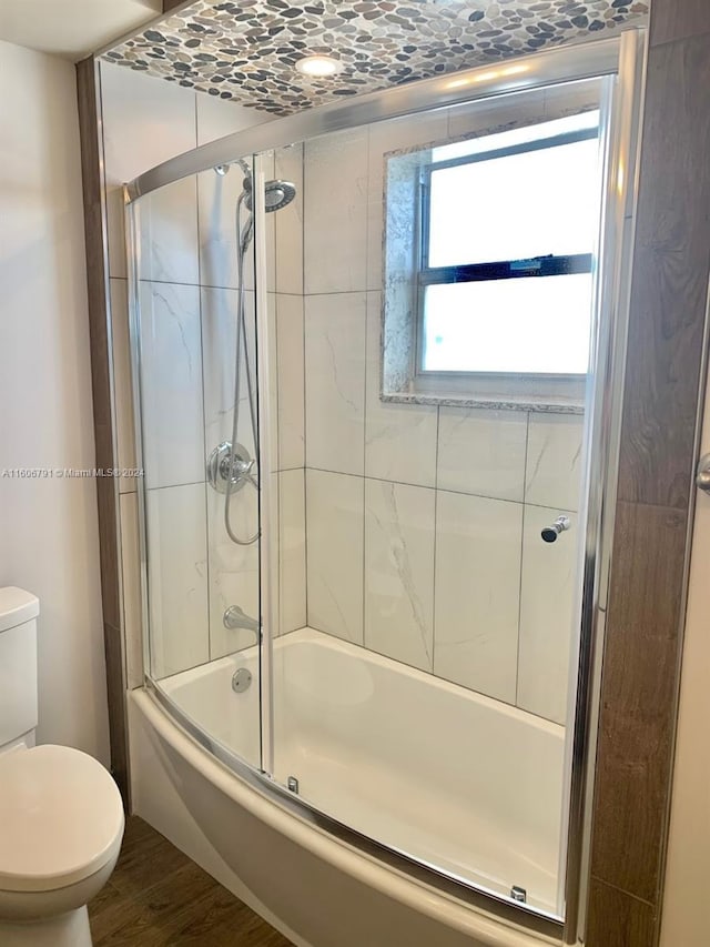 bathroom with wood-type flooring, toilet, and enclosed tub / shower combo