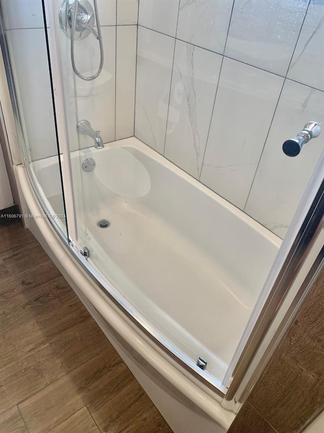 bathroom featuring wood-type flooring and enclosed tub / shower combo