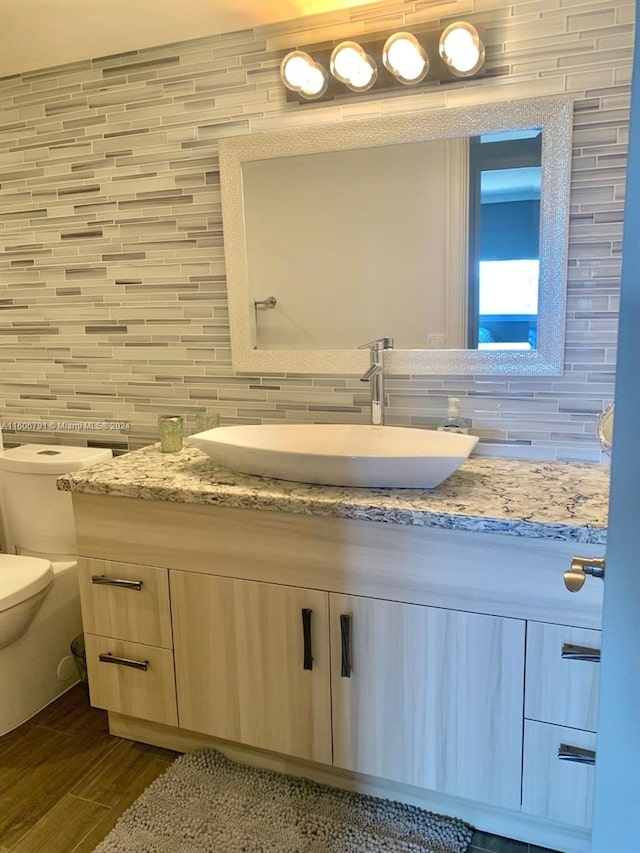 bathroom featuring tile walls, backsplash, toilet, and vanity