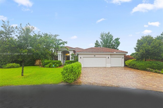 mediterranean / spanish house featuring a garage and a front yard