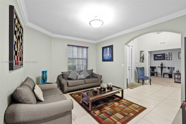 living room featuring ornamental molding, a textured ceiling, and light tile flooring