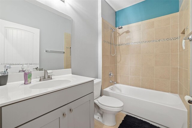 full bathroom with tiled shower / bath combo, large vanity, and toilet