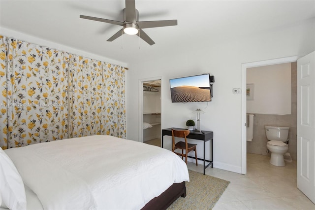 bedroom with ensuite bathroom, ceiling fan, light tile patterned floors, a closet, and a walk in closet