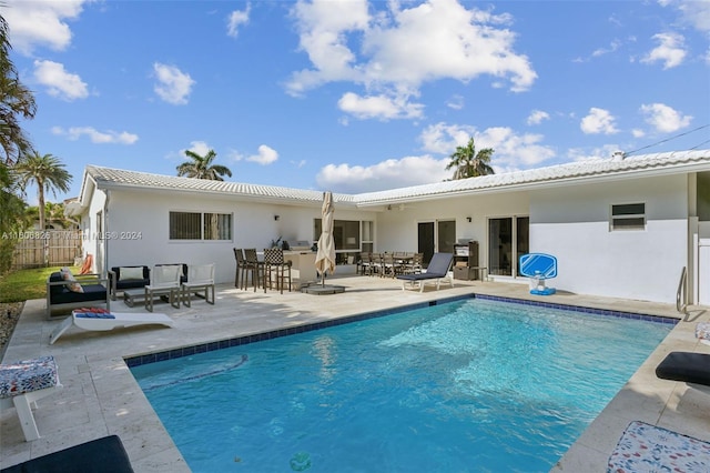 rear view of property with a bar, an outdoor hangout area, a fenced in pool, and a patio area