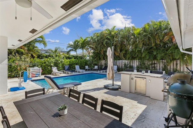 view of swimming pool with an outdoor kitchen, a patio, and ceiling fan