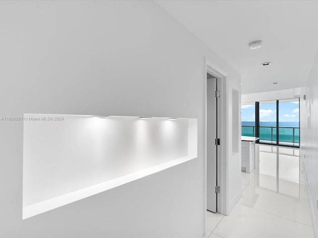 hall featuring light tile patterned floors and a water view