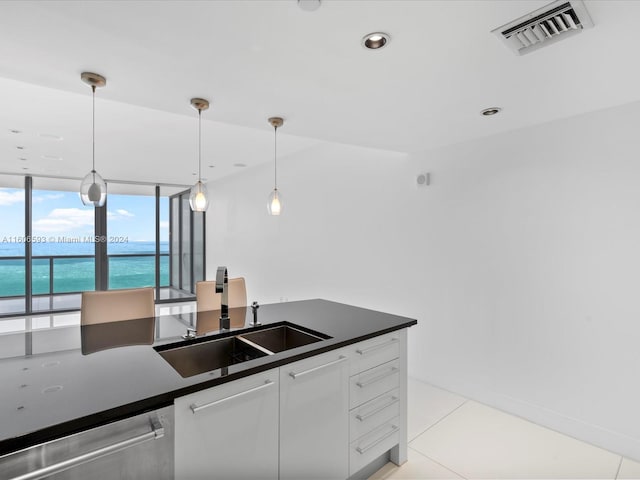 kitchen featuring white cabinetry, dishwasher, sink, hanging light fixtures, and a water view