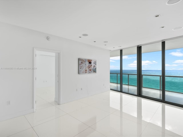 tiled spare room with floor to ceiling windows and a water view