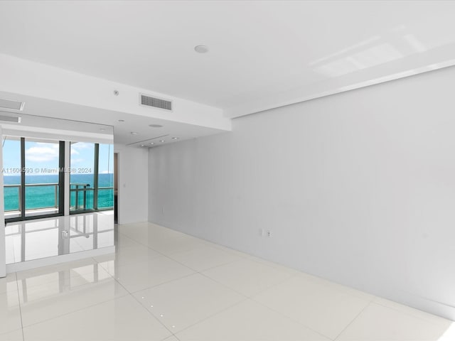 unfurnished room featuring a water view and light tile patterned floors