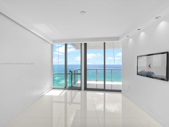 unfurnished room with a water view, light tile patterned floors, and a wall of windows