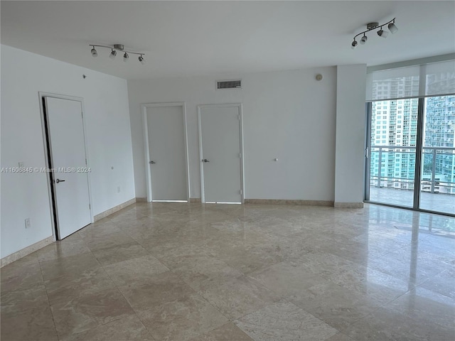 tiled spare room featuring expansive windows and rail lighting