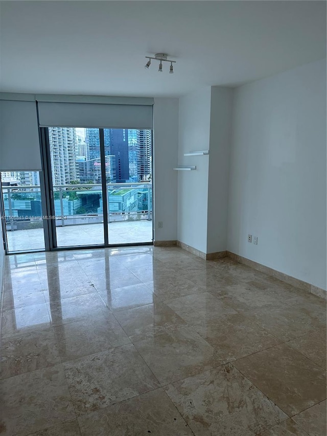 tiled empty room featuring expansive windows and track lighting