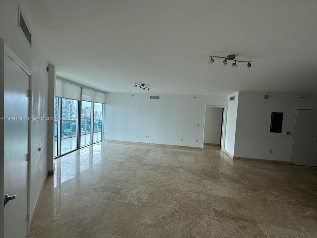 spare room featuring tile floors, floor to ceiling windows, and rail lighting