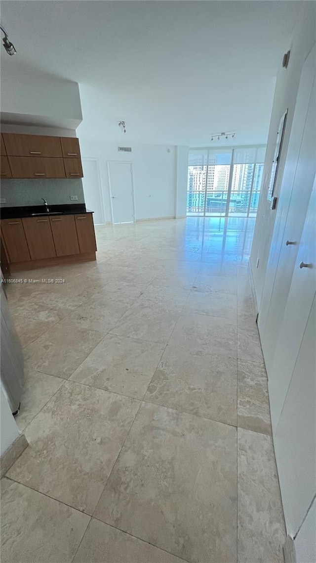 interior space featuring track lighting, sink, expansive windows, and light tile floors