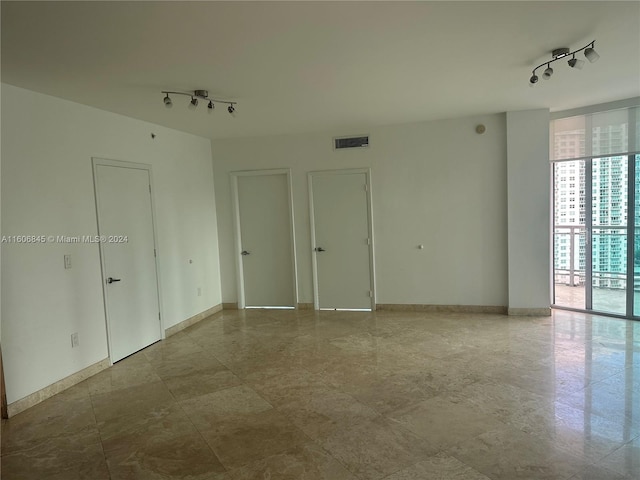 spare room featuring baseboards, visible vents, and rail lighting