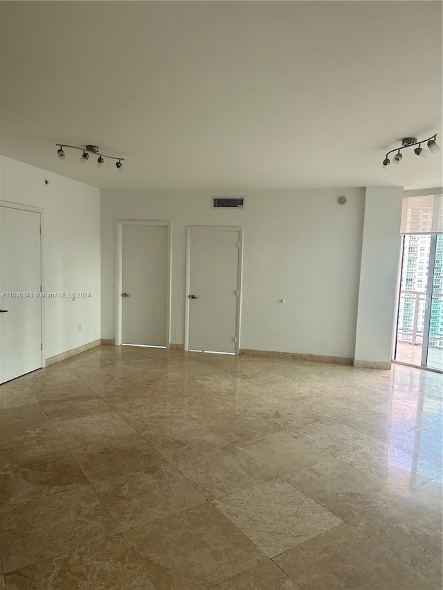 spare room with rail lighting, baseboards, and visible vents
