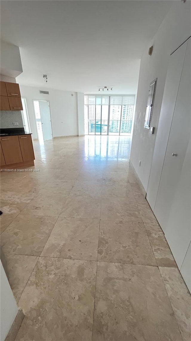 hall featuring track lighting, plenty of natural light, light tile flooring, and expansive windows