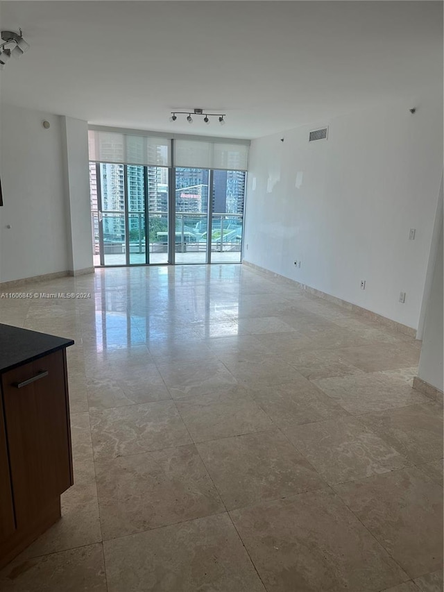 tiled spare room featuring floor to ceiling windows, track lighting, and plenty of natural light