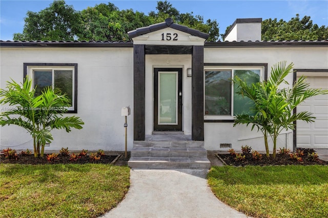 doorway to property featuring a lawn and a garage