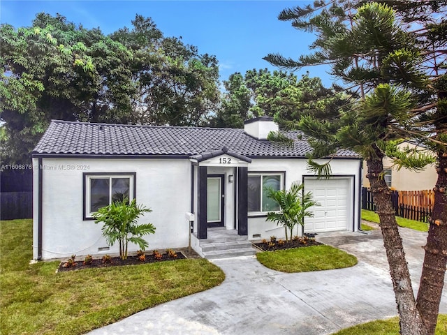 mediterranean / spanish home featuring a front yard and a garage