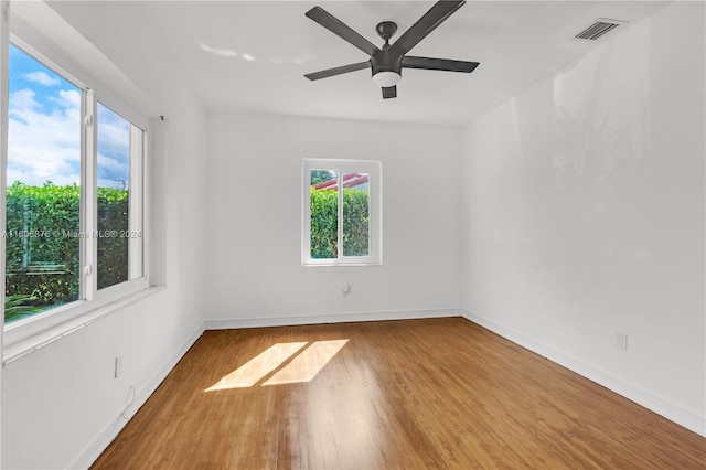 unfurnished room featuring plenty of natural light, ceiling fan, and hardwood / wood-style floors