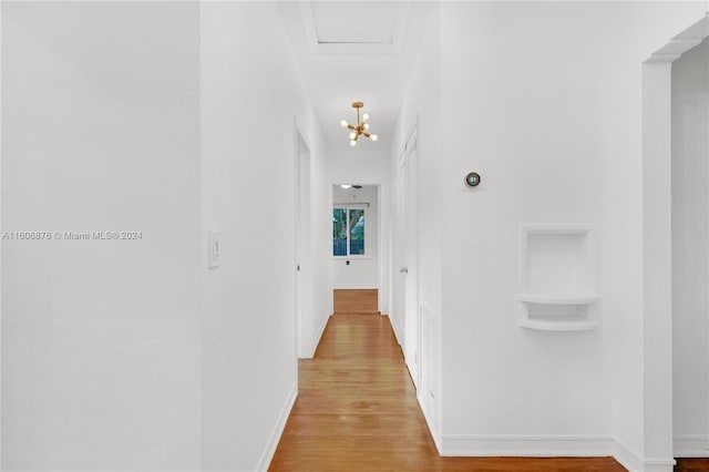 hallway with light wood-type flooring and a chandelier