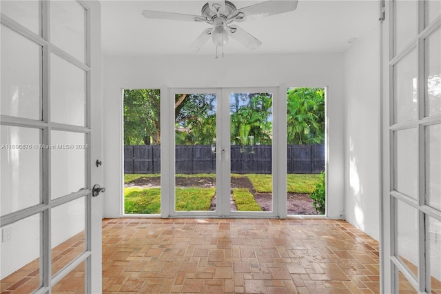 unfurnished sunroom with ceiling fan