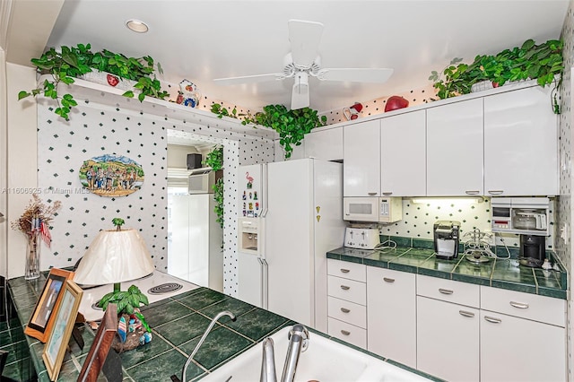 kitchen featuring white appliances, white cabinetry, and ceiling fan