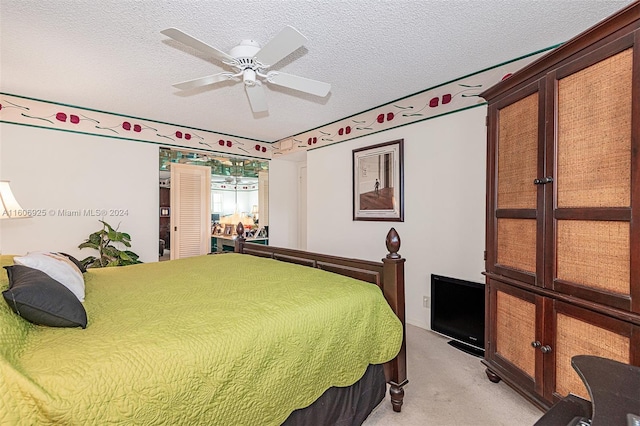 bedroom with ceiling fan, light colored carpet, and a textured ceiling