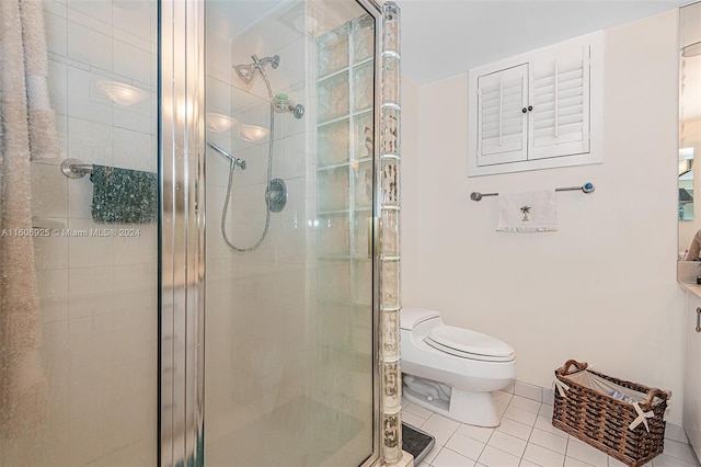 bathroom featuring toilet, tile patterned floors, and a shower with shower door