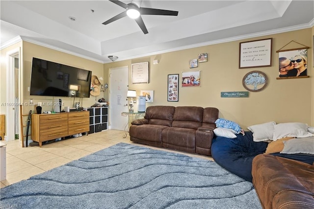 tiled living room with ceiling fan, a raised ceiling, and ornamental molding