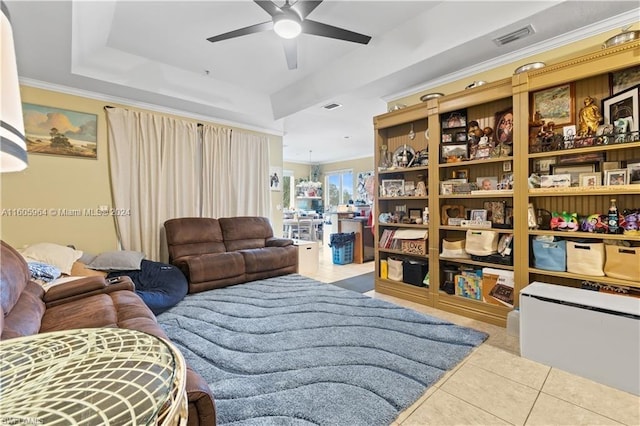 tiled living area featuring ceiling fan, visible vents, a tray ceiling, and ornamental molding