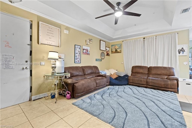 living area with visible vents, a raised ceiling, a ceiling fan, tile patterned floors, and crown molding