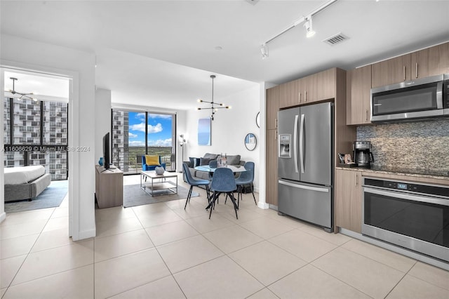 kitchen featuring an inviting chandelier, light tile patterned floors, stainless steel appliances, and tasteful backsplash