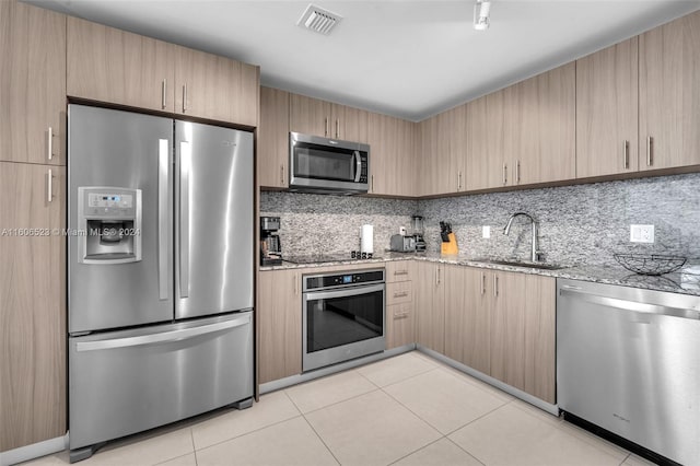 kitchen featuring light brown cabinetry, light stone countertops, sink, and appliances with stainless steel finishes