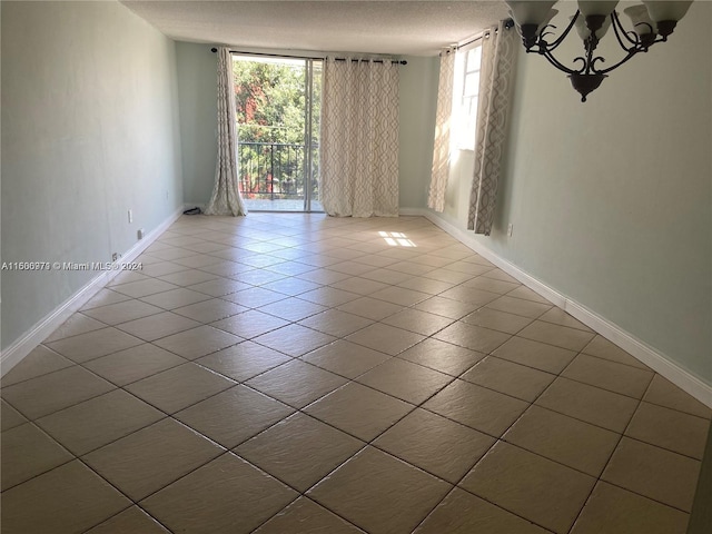 spare room featuring tile patterned floors, plenty of natural light, a textured ceiling, and a chandelier