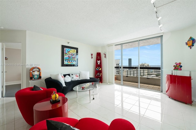 living room with tile floors, track lighting, a textured ceiling, and a wall of windows