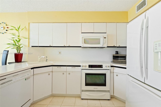 kitchen with a textured ceiling, white appliances, white cabinets, sink, and light tile flooring