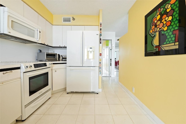 kitchen featuring a textured ceiling, white cabinets, white appliances, and light tile floors