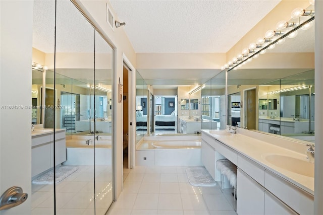 bathroom with a bathtub, a textured ceiling, vanity, and tile floors