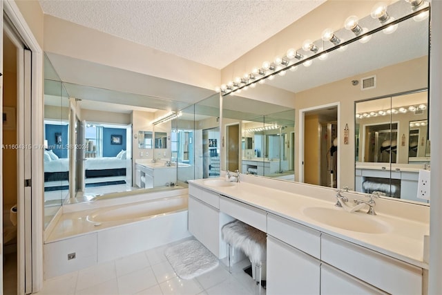 bathroom featuring tile floors, a bathtub, large vanity, double sink, and a textured ceiling