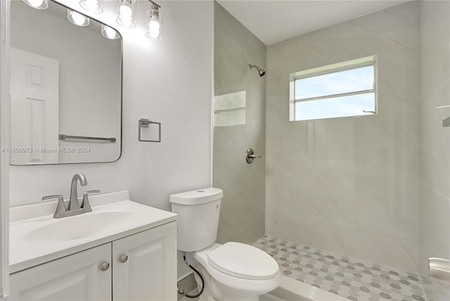 bathroom featuring toilet, vanity, and tiled shower