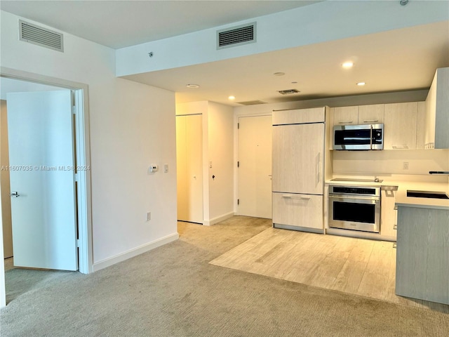 kitchen with appliances with stainless steel finishes, light carpet, and sink