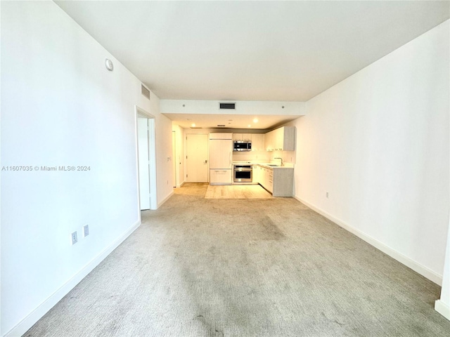 unfurnished living room with light carpet and sink