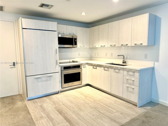 kitchen featuring stainless steel appliances, sink, and light wood-type flooring